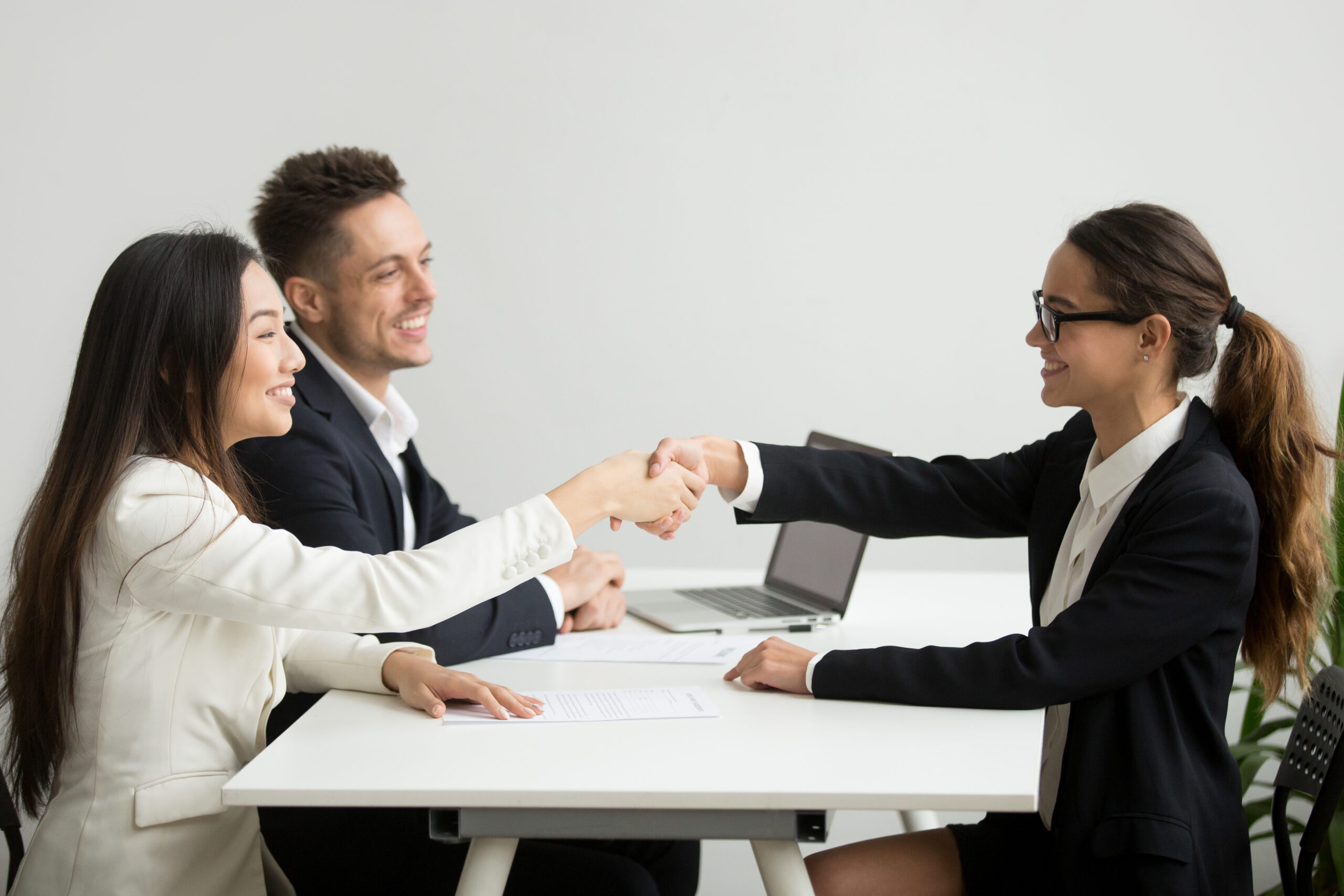 Smiling diverse businesswomen shake hands at group meeting, deal Smiling diverse businesswomen shake hands at group meeting, friendly asian hr handshaking congratulating hired applicant at job interview, satisfied millennial partners make contract deal concept